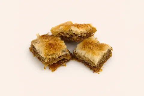 Three pieces of golden, flaky baklava layered with nuts